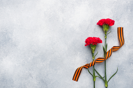 Red carnations and St. George ribbon on a concrete background. Symbol may 9, victory day. Copy spaceの写真素材