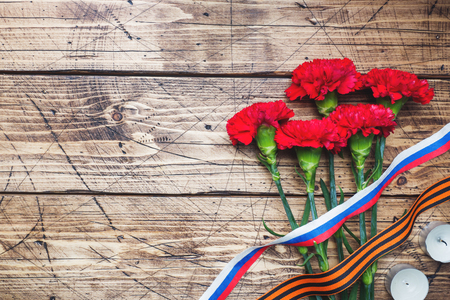 Red carnations and St. George ribbon on wooden background. Symbol may 9, victory day. Copy spaceの写真素材