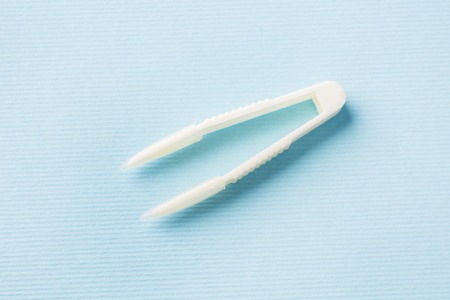 White plastic tweezers with soft tips on blue background.の写真素材