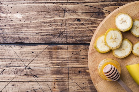 Banana and sliced banana into pieces with honey on wooden background, copy spaceの写真素材