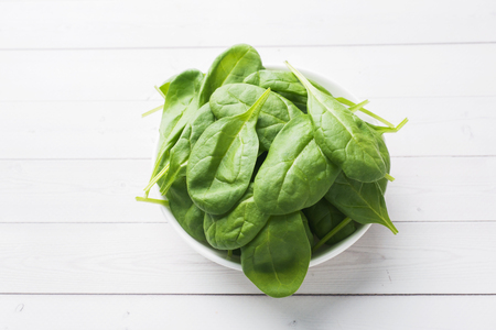 Fresh spinach leaves in a plate on a light tableの写真素材