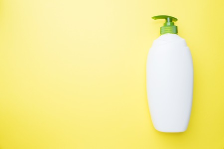 White empty liquid bottle on yellow background. Home cleaning concept. Top view, copy spaceの写真素材