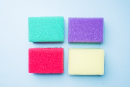 Cleaning colors sponges and brushes on blue background. Home cleaning concept. Top view, copy spaceの写真素材