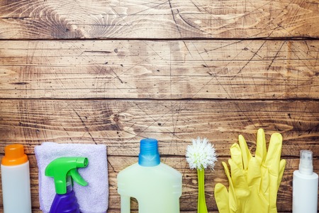 Bottles with detergents, brushes and sponges on wooden background. Colorful cleaning products. Home cleaning concept. Top view, copy spaceの写真素材