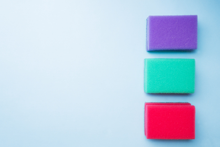 Cleaning colors sponges and brushes on blue background. Home cleaning concept. Top view, copy spaceの写真素材