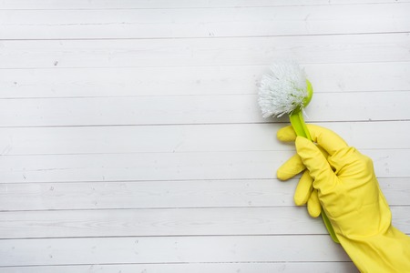 Hand in yellow glove and cleaning sponge for cleaning on wooden background. Home cleaning concept. Top view, copy space,の写真素材