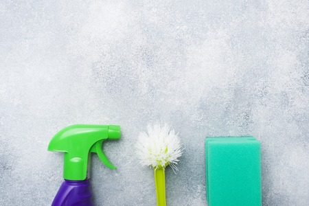 Bottles with detergents, brushes and sponges on concrete background. Colorful cleaning products. Home cleaning concept. Top view, copy spaceの写真素材