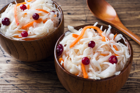 Homemade sauerkraut with carrots and cranberries in wooden bowlsの写真素材