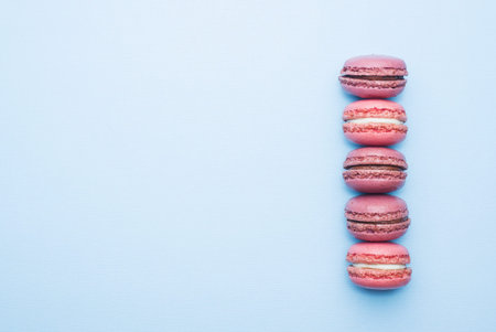 Pink dessert macaron or macaroon on blue  top view. Flat lay Copy space