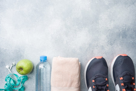 Healthy lifestyle, food and water, athlete's equipment on grey background. Flat lay. Top view with copy spaceの写真素材
