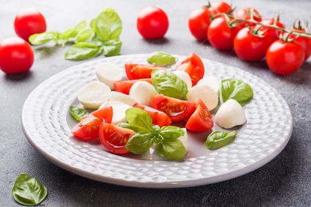 Caprese salad of tomatoes, mozzarella cheese and Basil on a dark background. Italian cuisineの写真素材