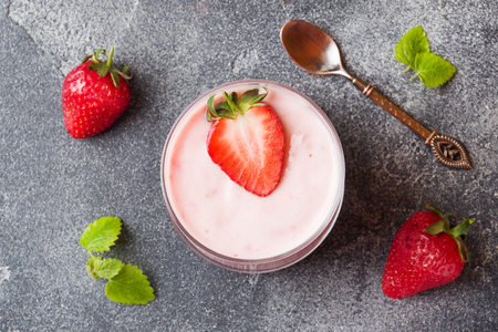 Homemade yogurt with fresh strawberries in glasses on a dark concreteの写真素材