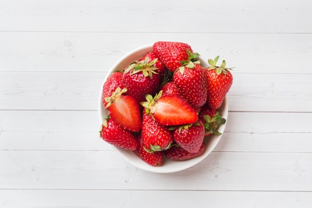 Fresh strawberries in a ceramic plate on a white table. Copy spaceの写真素材