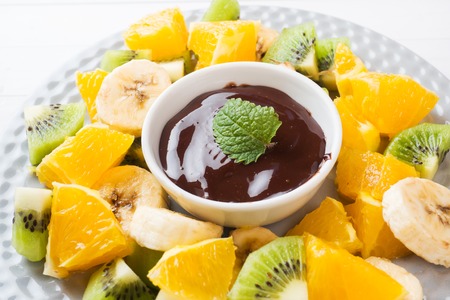 Chocolate fondue with fruit on white table. concept summer partyの写真素材