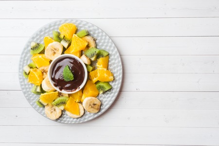 Chocolate fondue with fruit on white table. concept summer party Copy spaceの写真素材