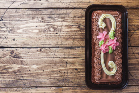 Chocolate rectangular cake decorated with cream roses on a wooden background. Sweet food is a confectionery business. Top view copy space,の写真素材