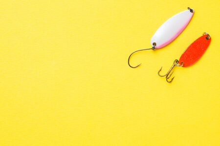 Fishing hooks and baits in a set for catching different fish on a yellow background with copy space. Flat lay,の写真素材