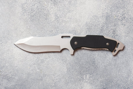 Steel knife for hunting and tourism on a gray concrete background