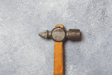 An old hammer on a wooden handle. Gray concrete background