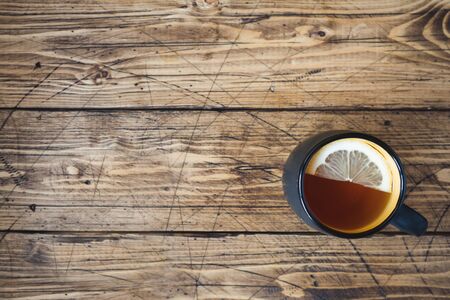 Black mug with tea and lemon on wooden table. Copy space top viewの写真素材