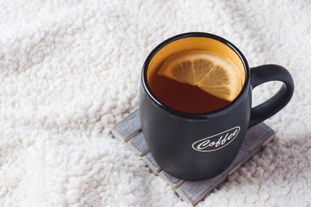 Black mug with tea and lemon on a warm soft blanket. Copy space top viewの写真素材