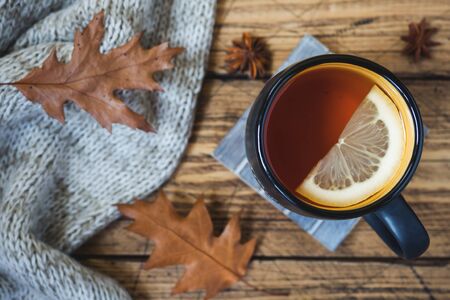 Autumn still life with cup of tea, cookies, sweater and leaves on wooden background. concept of cozy autumn, fall season.の写真素材