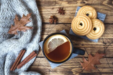 Autumn still life with cup of tea, cookies, sweater and leaves on wooden background. concept of cozy autumn, fall season.の写真素材