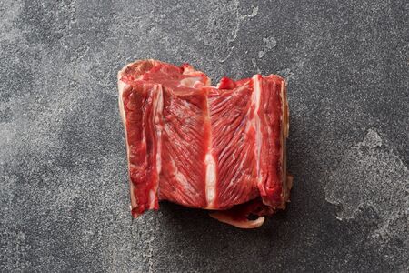 Fresh raw piece of beef rib with meat on a dark concrete background with copy spaceの写真素材