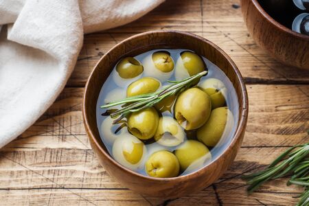Black and green olives in wooden bowls on wooden table. Top view with space for textの写真素材