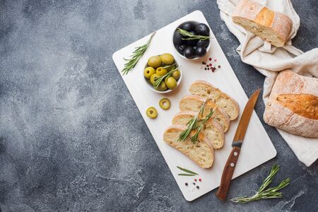Italian ciabatta bread with olives and rosemary on a cutting Board. Dark concrete background Copy space.の写真素材