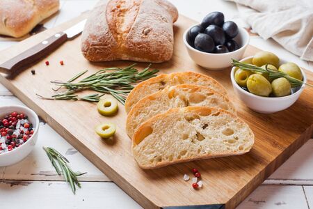 Italian ciabatta bread with olives and rosemary on a wooden Boardの写真素材