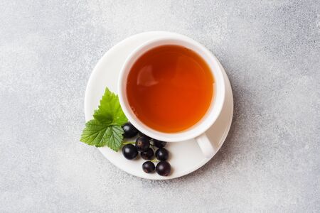 Cup of tea and fresh blackcurrant berries on grey table. Copy spaceの写真素材