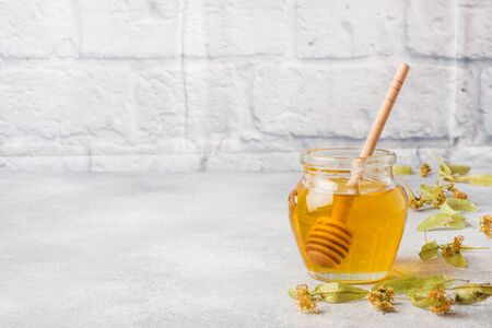 jar of liquid honey from Linden flowers and a stick on grey concrete background. Copy spaceの写真素材