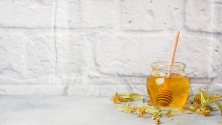 jar of liquid honey from Linden flowers and a stick on grey concrete background. Copy spaceの写真素材