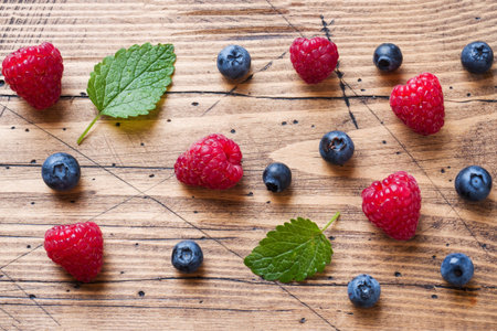 Fresh raspberries and blueberries in a wooden background