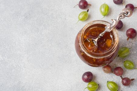 Gooseberry jam in a jar with fresh gooseberry berries on a gray background Copy space.の写真素材