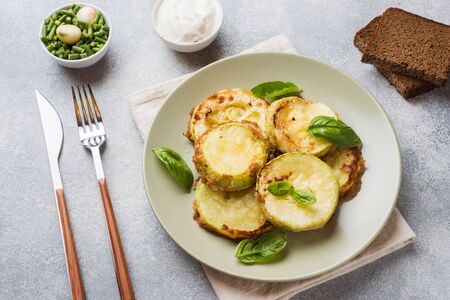 Slices of fried zucchini in batter with garlic and Basil on a plateの写真素材