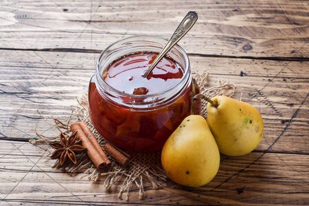 Homemade pear jam in a jar and fresh pears on a wooden background Copy space.の写真素材