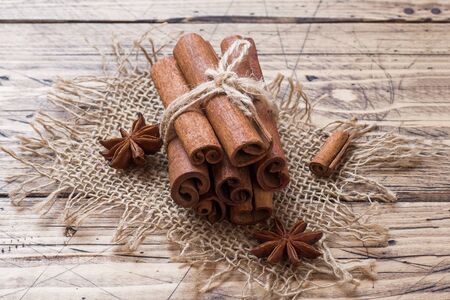 A few cinnamon sticks tied with thread and anise stars on a wooden background. Copy space. Selective focusの写真素材
