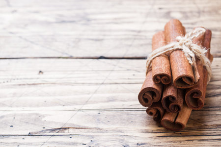 Several cinnamon sticks tied with thread on a wooden background. Copy space. Selective focus