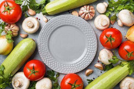 Set of different seasonal vegetables on a gray concrete background. Tomato zucchini onion garlic mushrooms parsley spices. Frame copy spaceの写真素材