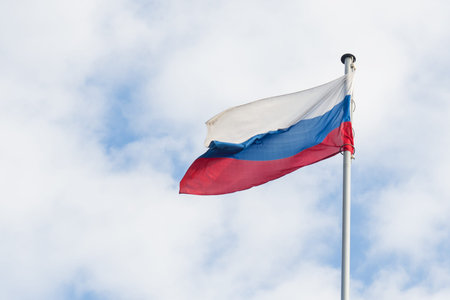 The Russian flag flies in the wind against the blue sky