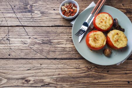 Baked whole tomatoes stuffed with mushrooms and cheese with seasonings on a wooden background Copy space.の写真素材