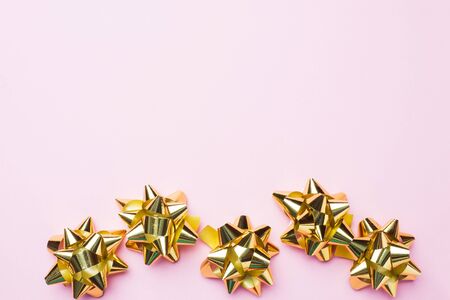 Gold Christmas bows on pink background. Gift concept greetings for holidays birthday Wedding New year Christmas mother's Day. Copy spaceの写真素材