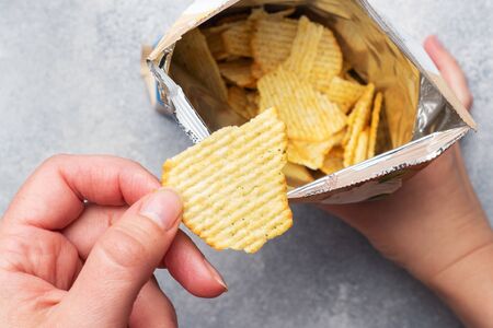 Potato chips with spicy in an open package hold hands. Close up Selective focusの写真素材