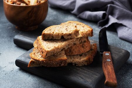 Slices of wholegrain bread on a wooden cutting Board. Dark concrete backgroundの写真素材