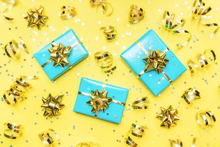 Gift boxes with gold ribbons and bows, confetti stars on a yellow background. Copy space Flat lay Greeting card for birthday party, Christmas Wedding mother's Day.の写真素材