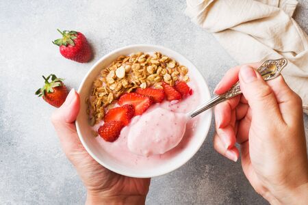 Homemade yogurt with fresh strawberries and muesli. The concept of a healthy Breakfast. Hands in shotの写真素材