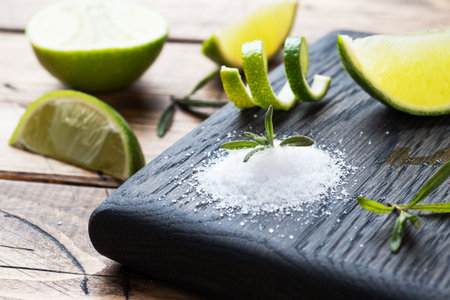 Slices of fresh lime, salt and rosemary on a wooden cutting Board