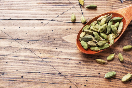 Whole grains of cardamom, a stick of cinnamon star anise and cane sugar. Copy space. Ingredients for making the Indian drink masala tea. wooden backgroundの写真素材